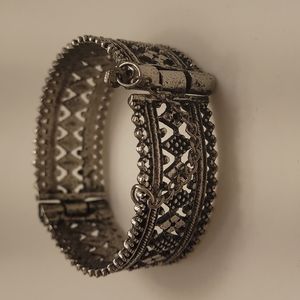 Open silvertone bracelet cuff with closer screw barrel.